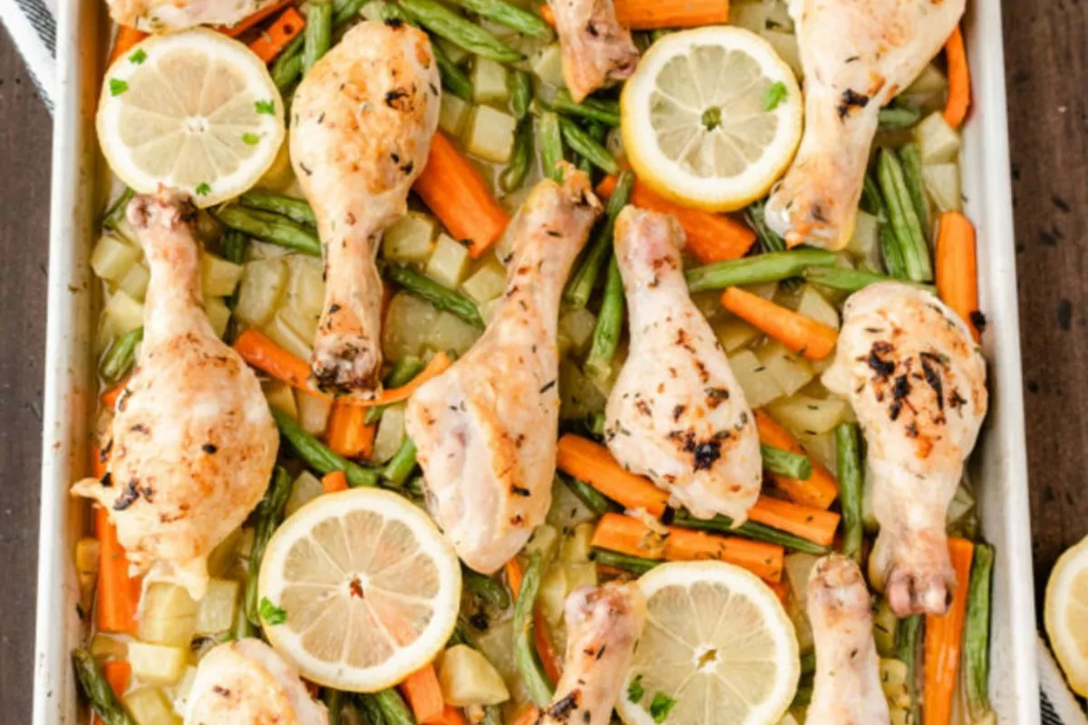 a sheet pan of baked chicken legs with vegetables