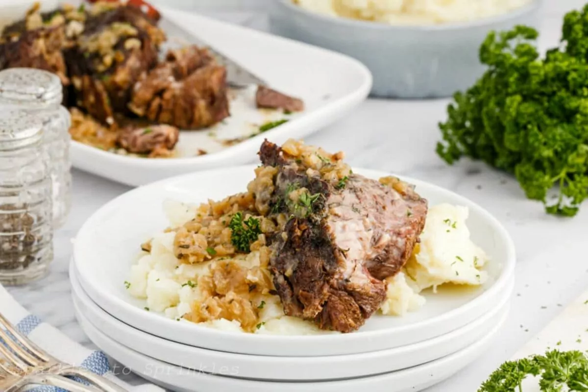 a plate of beef with mashed potato and top with gravy