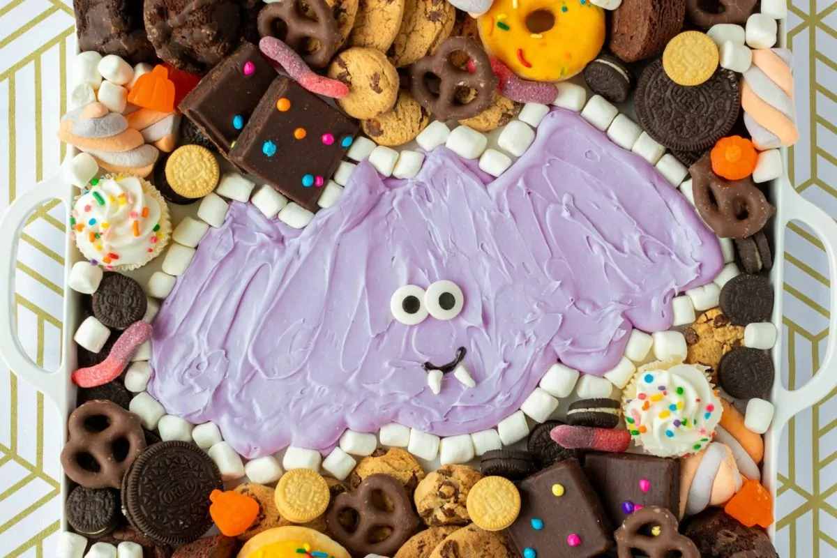 A cute bat-shaped frosting design Halloween charcuterie board with chocolate chip pretzel cookies chocolate