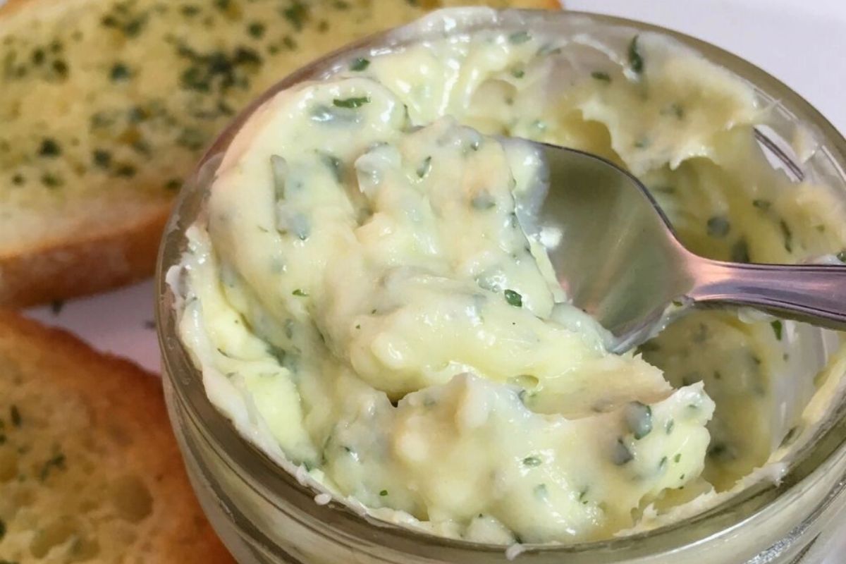 small mason jar with homemade garlic butter with spoon.