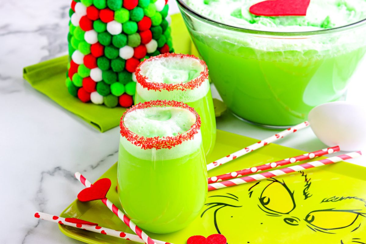 two glass of green punch with red sprinkles and foam on top