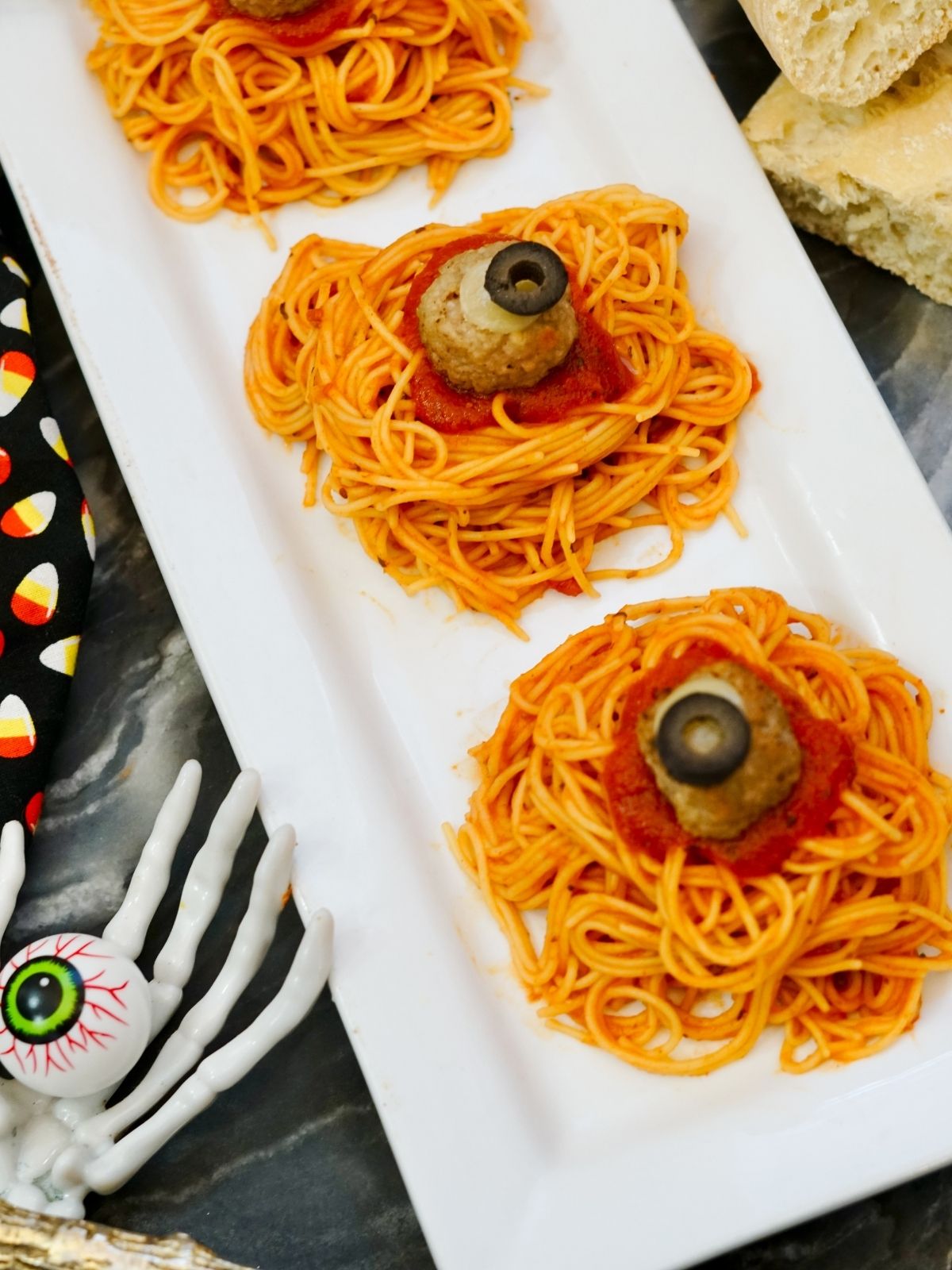 spaghetti with sauce, meatballs on white plate decorated for Halloween.