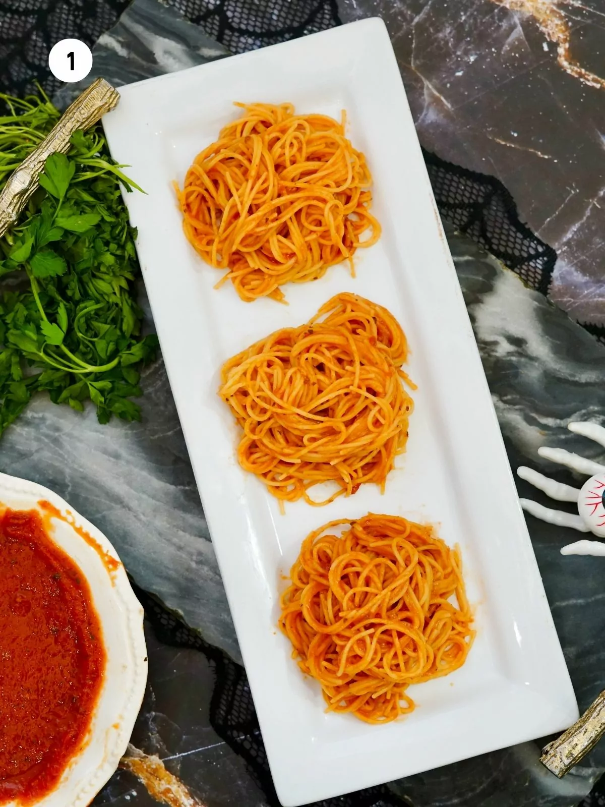 3 mounds of spaghetti on white plate with bowl of tomato sauce.