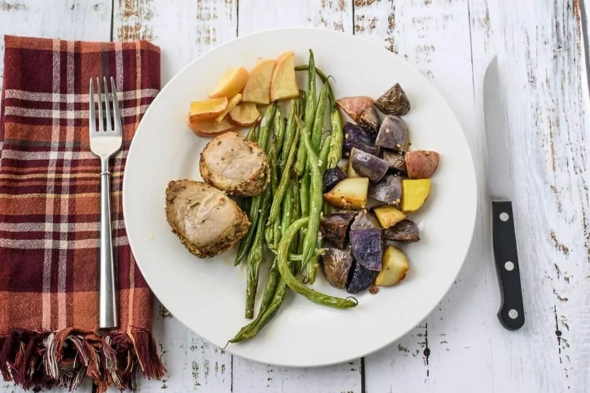 a sheet pan of baked potatoes, green beans and juicy pork chunks