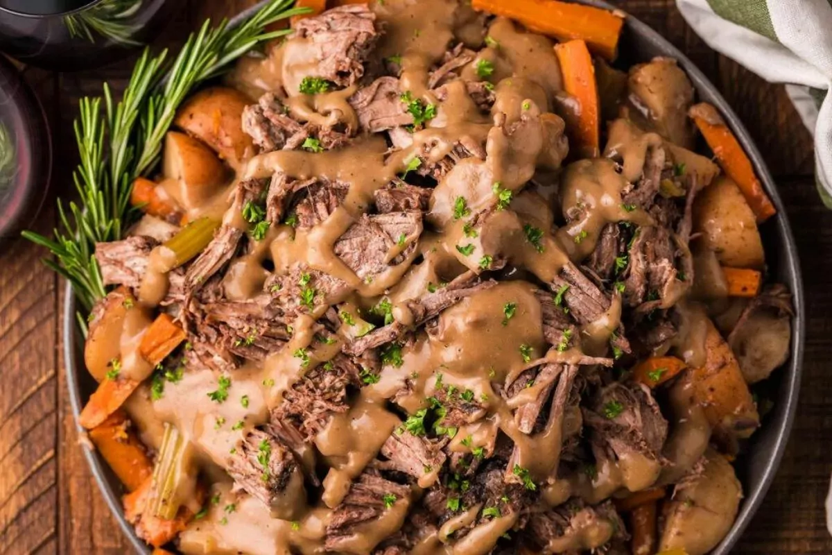 a plate of beef with potato and carrots sprinkle with rosemary leaves