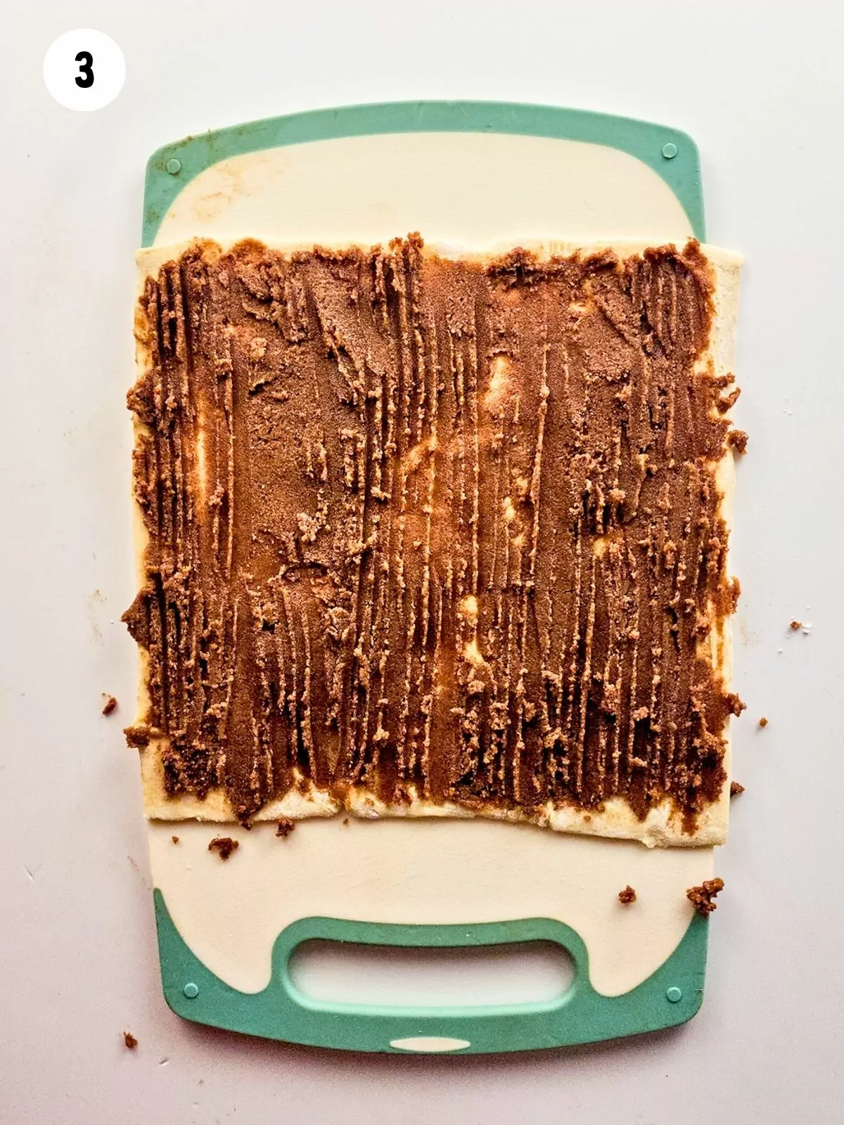 puff pastry sheet spread with brown sugar mixture on cutting board.