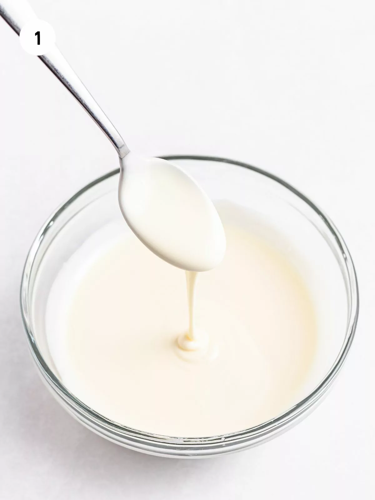 melted white chocolate dripping from a spoon into a bowl