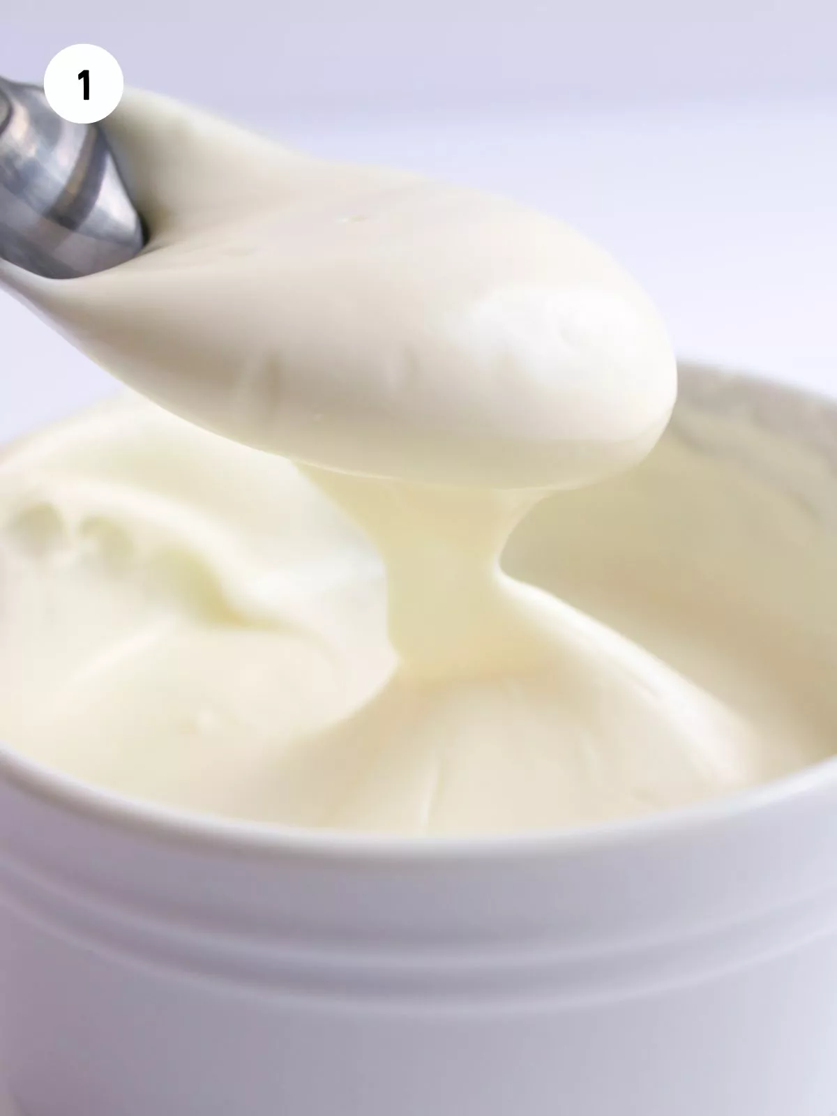 melted white chocolate in a bowl with a spoonful above it.