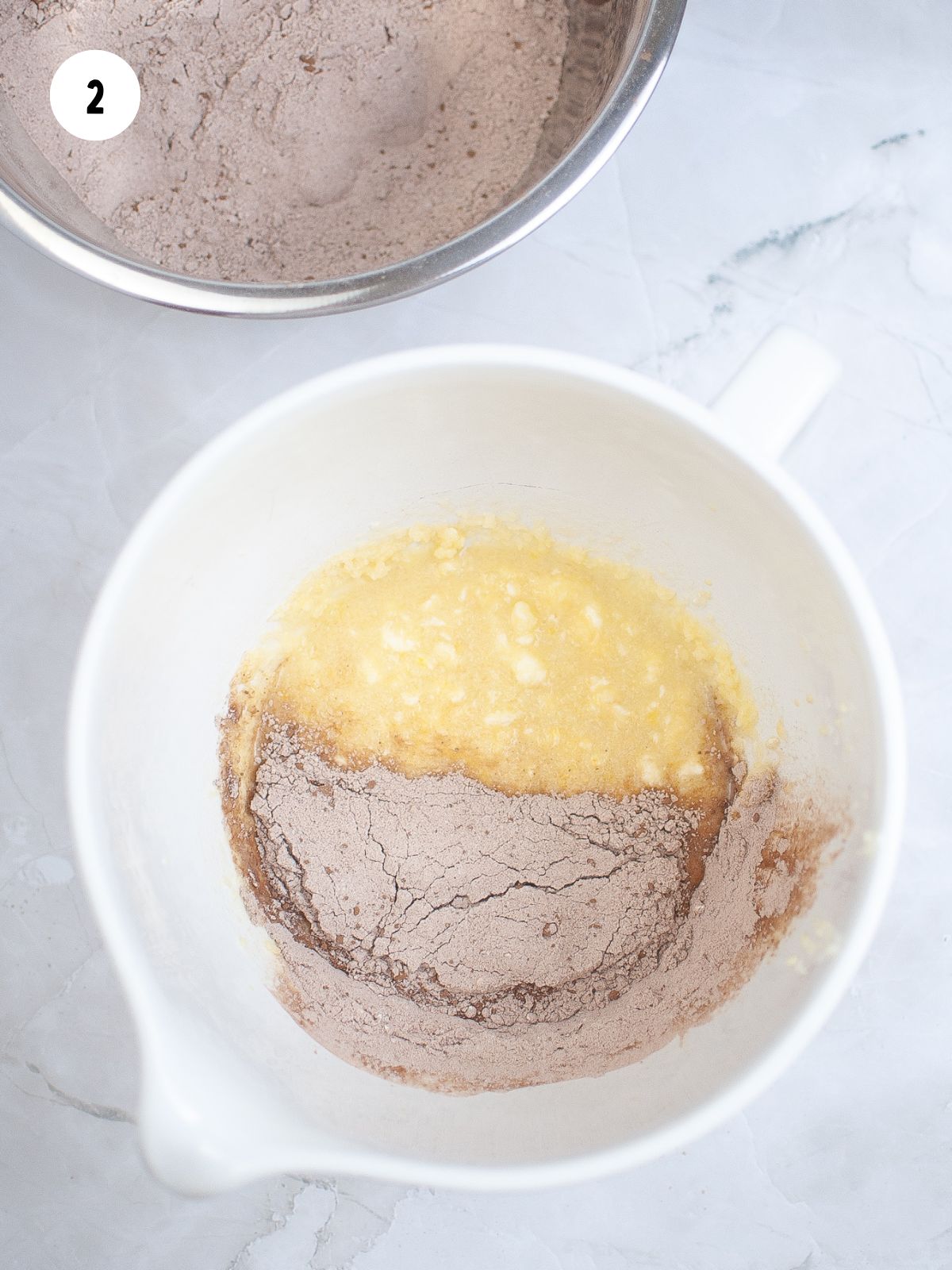 a white mixing bowl filled with the wet ingredients and half the dry ingredients