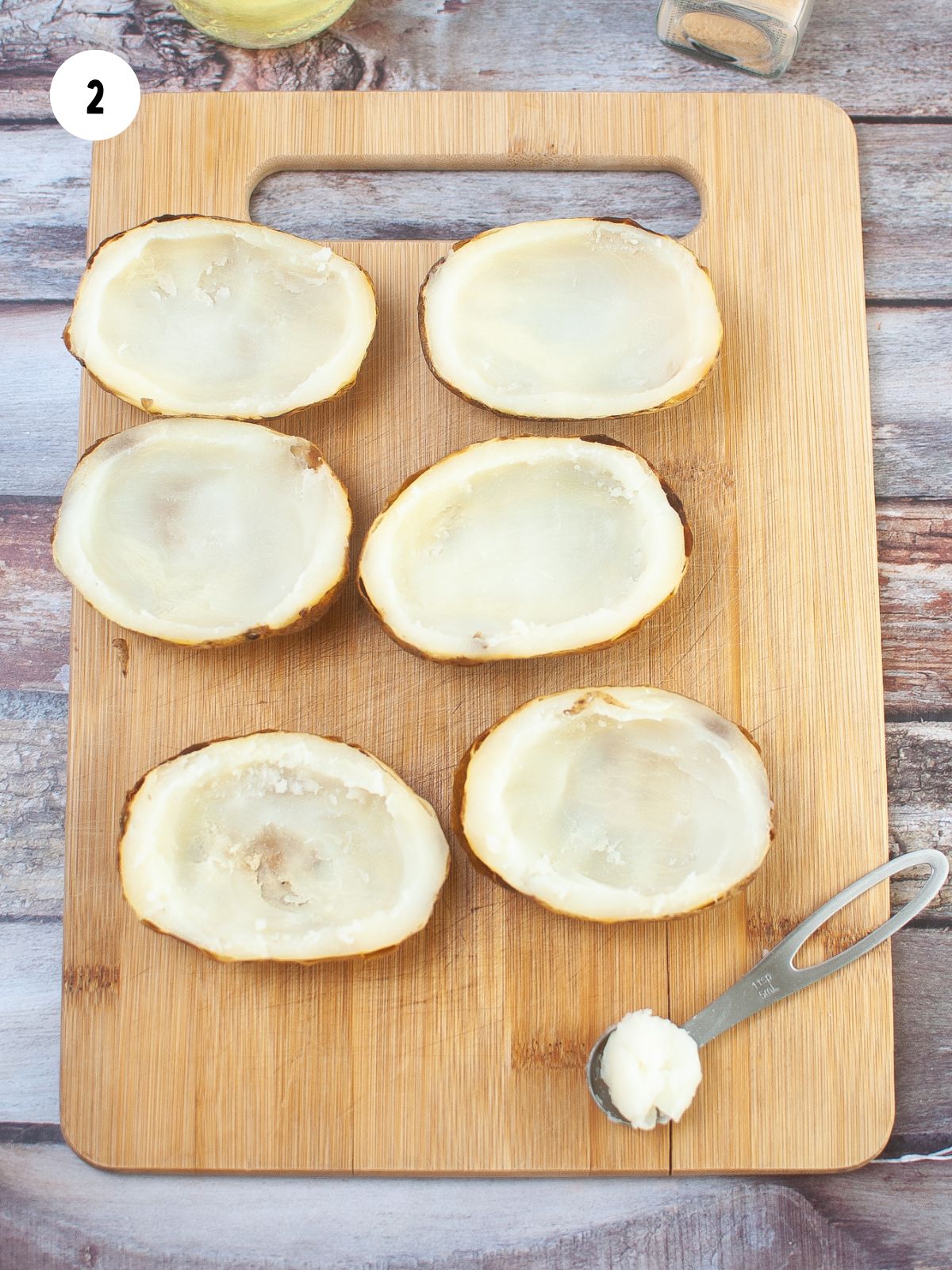 potato halves with the flesh scooped out on a wood cutting board