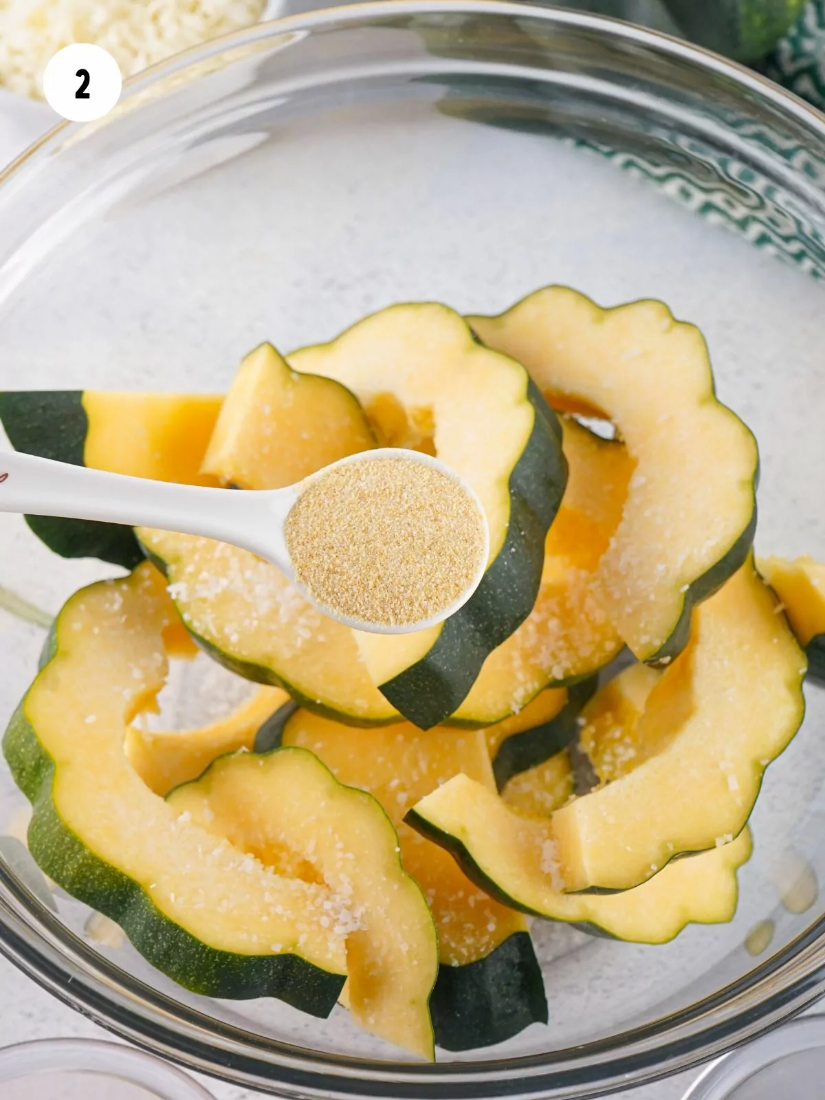 teaspoon of garlic powder over a bowl of sliced acorn squash