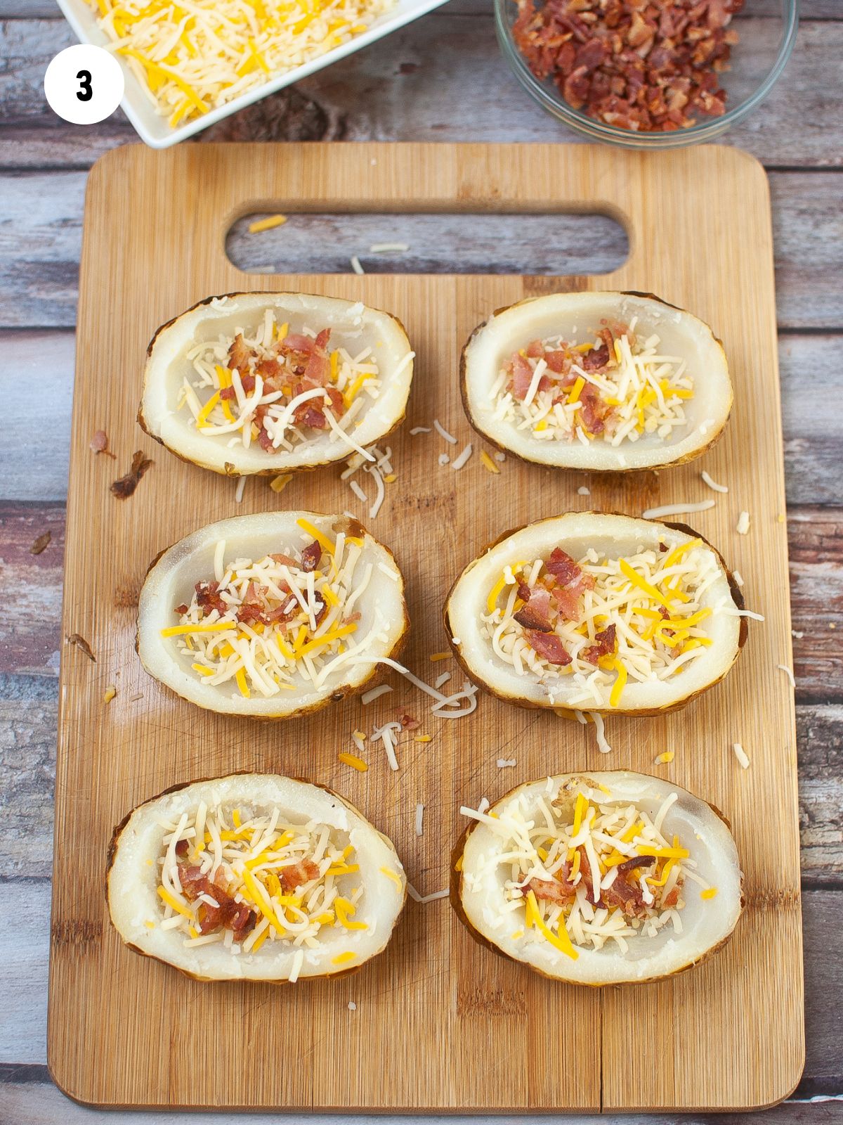 potato skins with bacon and cheese on top on a wood cutting board