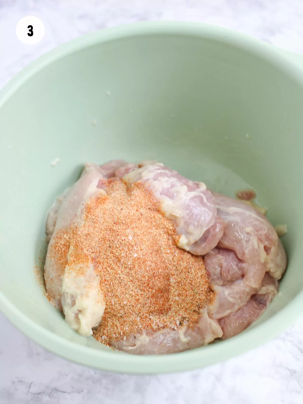 seasonings added to the chicken thighs in a bowl