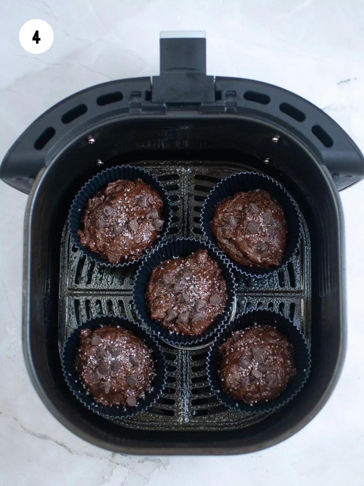 chocolate chocolate chip muffins in silicone muffin liners in the air fryer basket