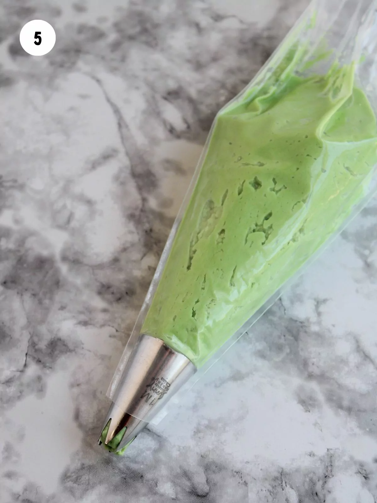 green frosting in a piping bag fitted with a piping tip