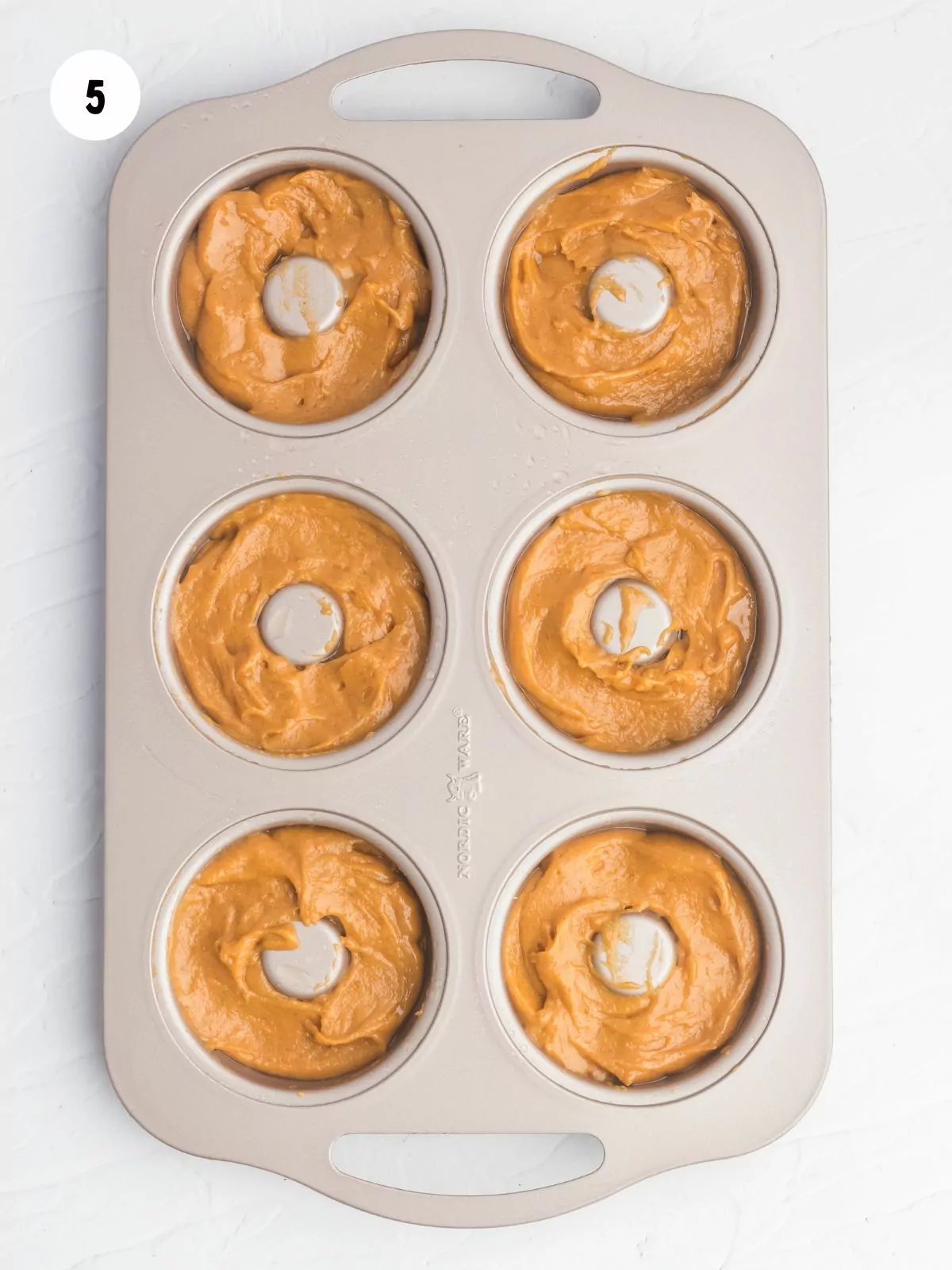 pumpkin donut batter in a donut pan