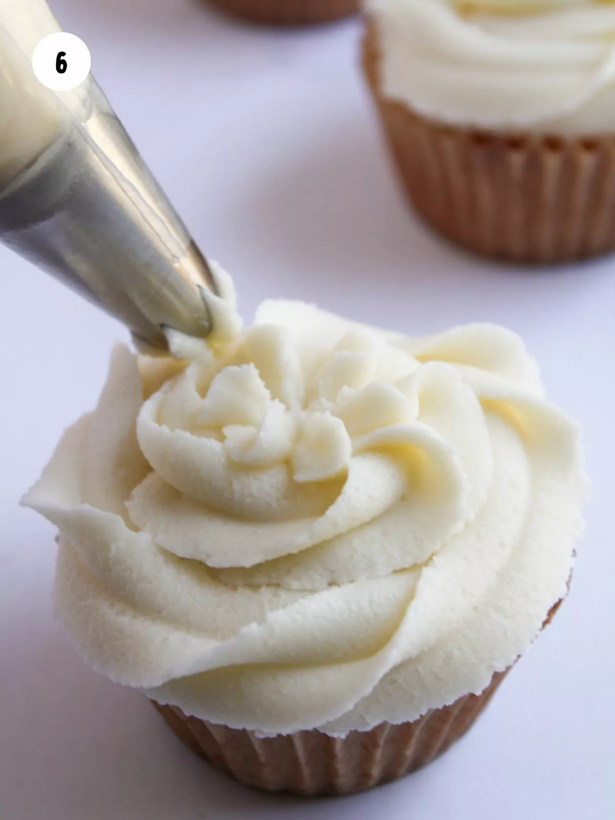 frosting being piped onto a cupcake