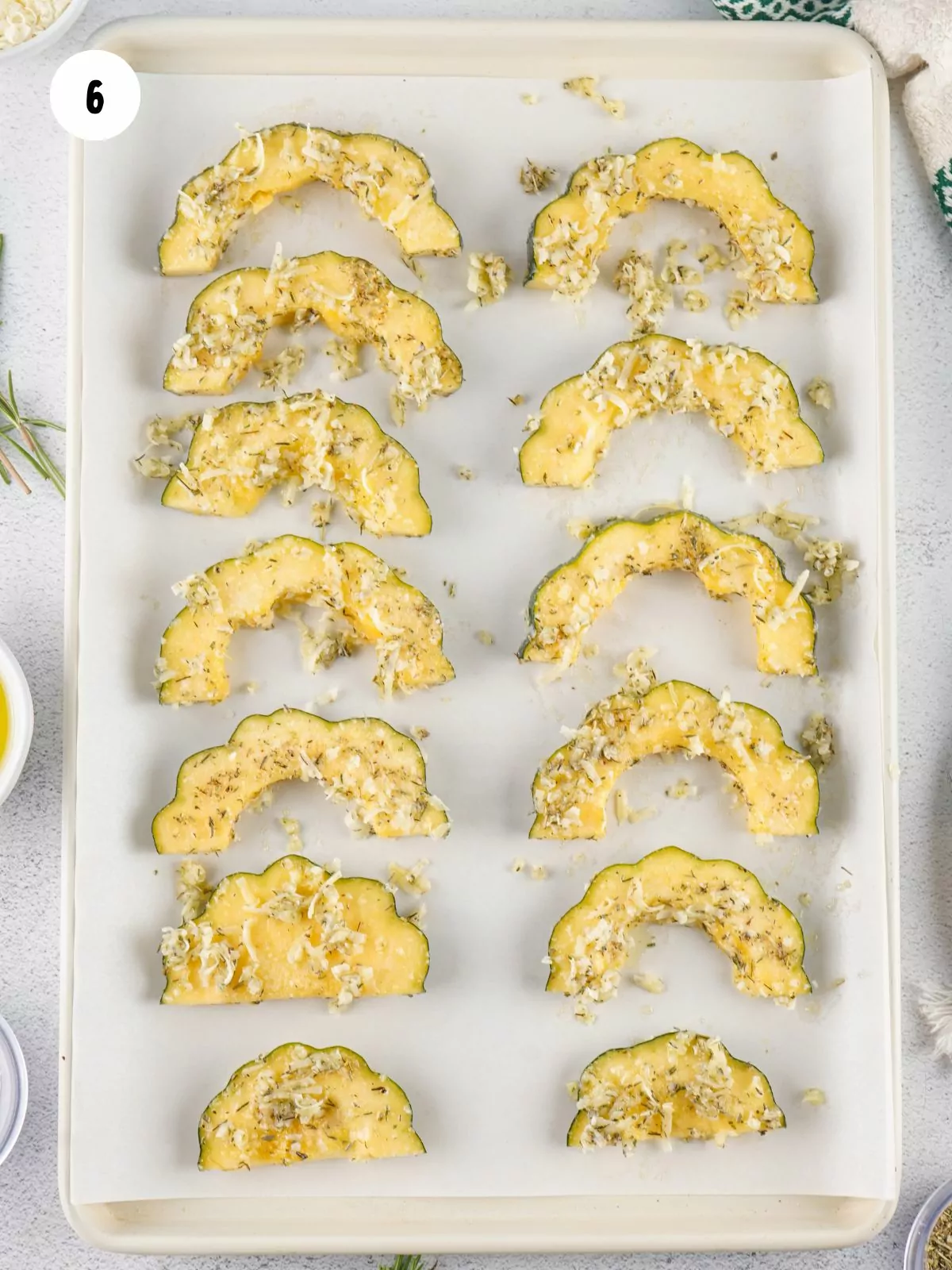 seasoned acorn squash laid out in a single layer on a baking sheet