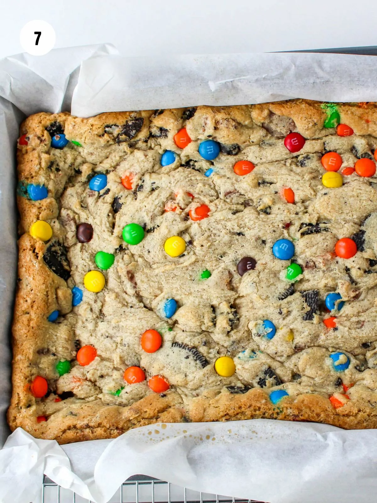 baked cookie bars in a parchment lined baking pan