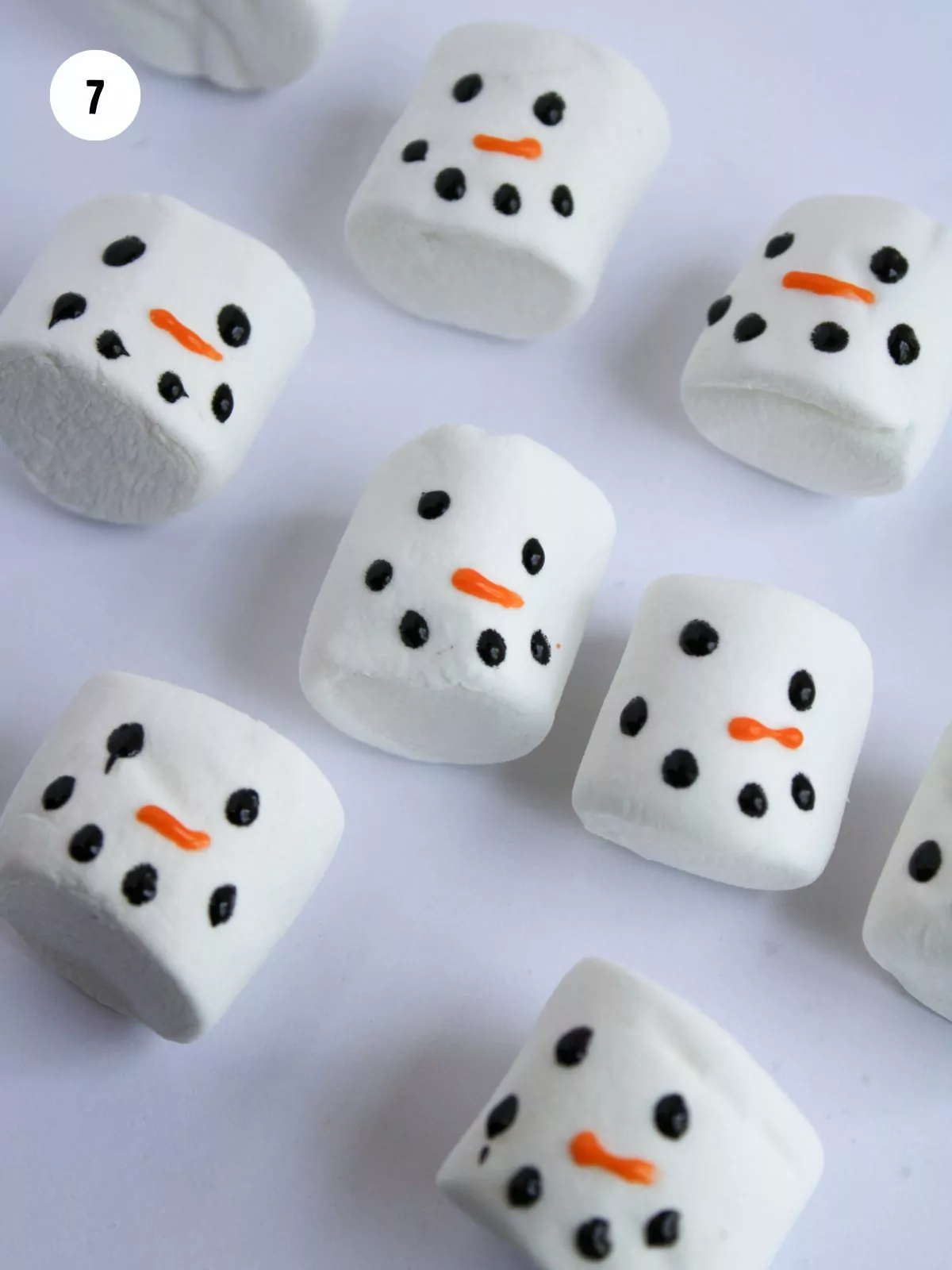 snowman face piped onto marshmallows with black and orange icing