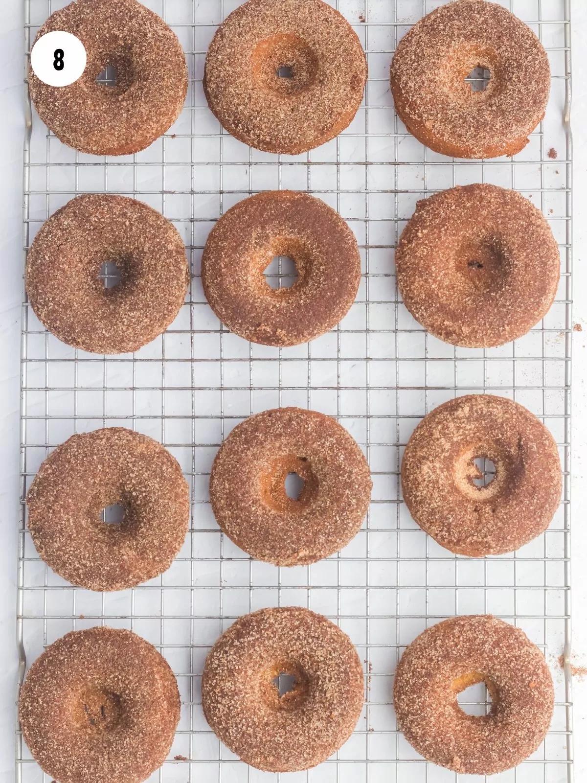 pumpkin donuts with cinnamon sugar topping on a wire cooling rack