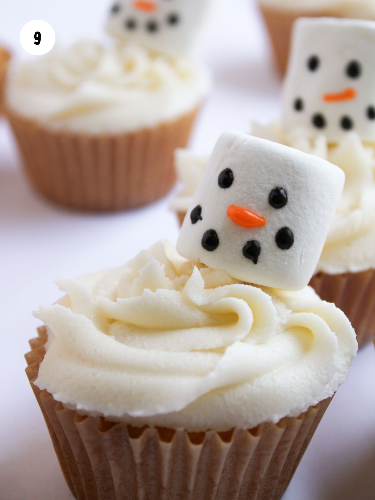 Snowman marshmallow face stuck onto a frosted cupcake