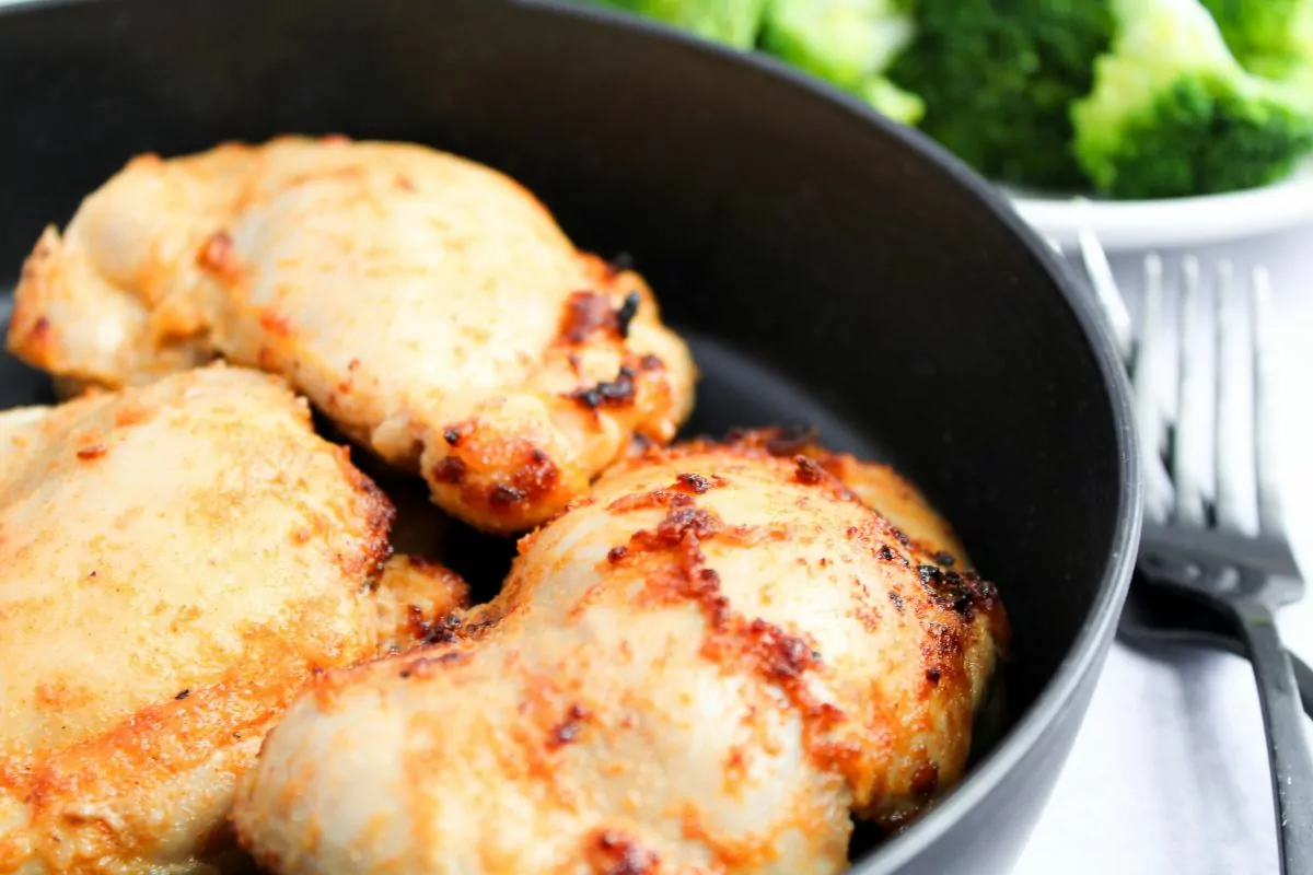 Air Fryer Chicken Thighs in a black bowl with a fork next to it