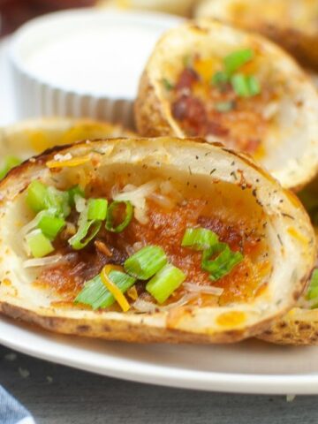 close up of a potato skin with cheese, bacon, and green onions cooked in the air fryer