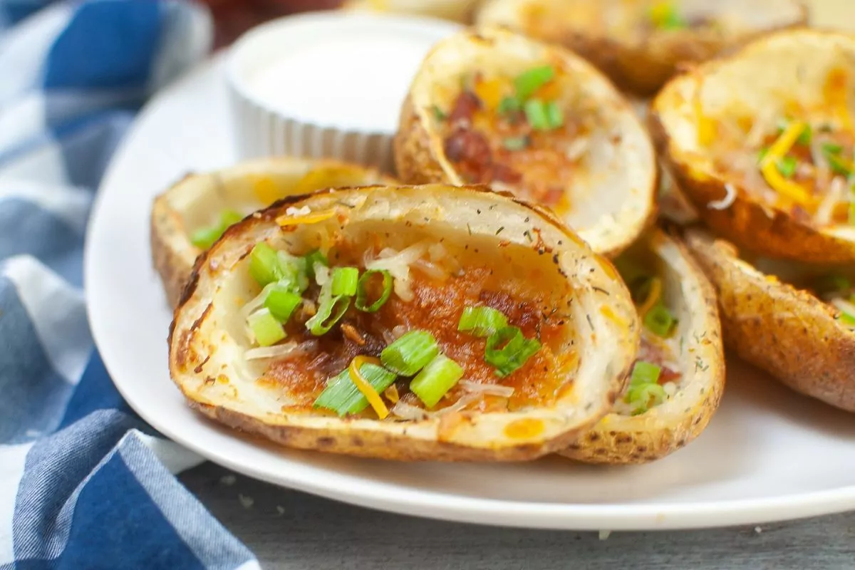 close up of a potato skin with cheese, bacon, and green onions cooked in the air fryer