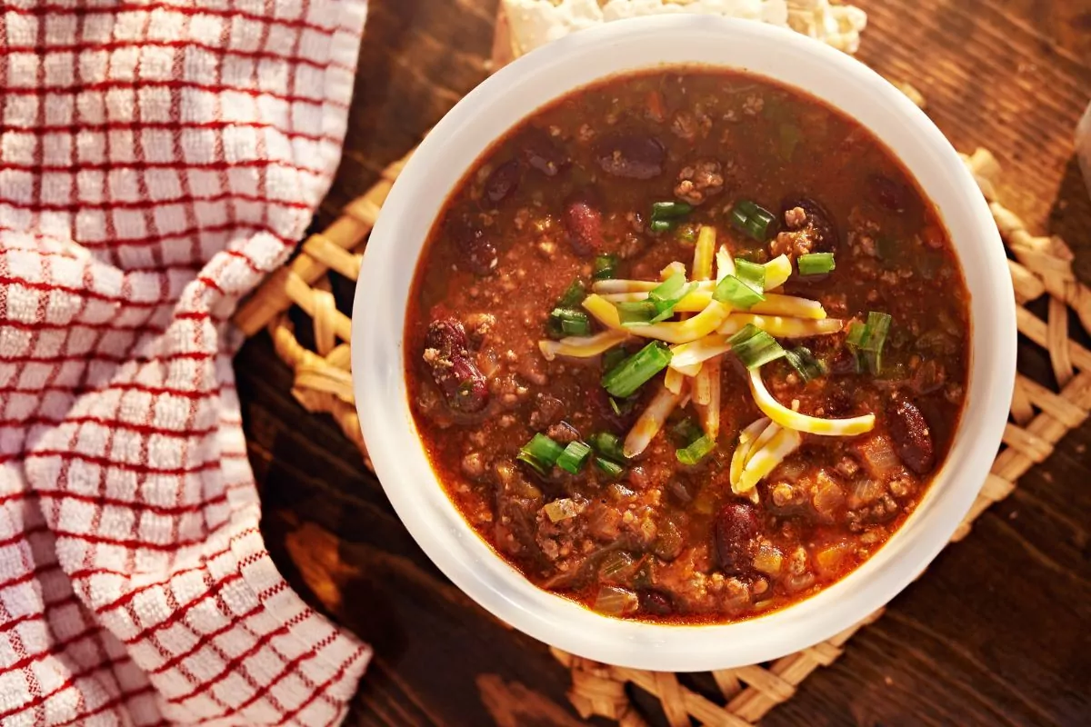 bowl of chili with cheese and green onions.