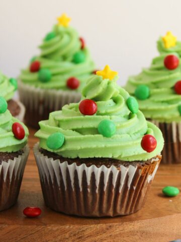 Chocolate cupcakes decorated like a Christmas tree with green frosting, candy, and sprinkles