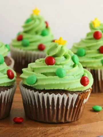 Chocolate cupcakes decorated like a Christmas tree with green frosting, candy, and sprinkles