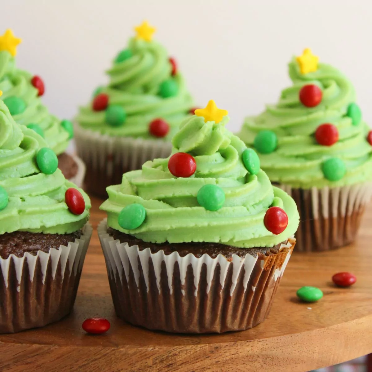 Chocolate cupcakes decorated like a Christmas tree with green frosting, candy, and sprinkles