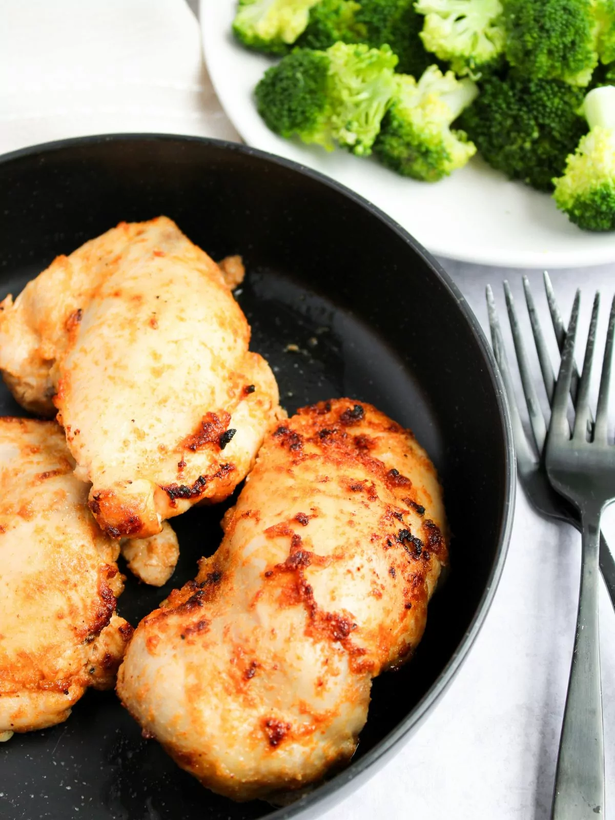 Air Fryer Chicken Thighs with a plate of broccoli in the background