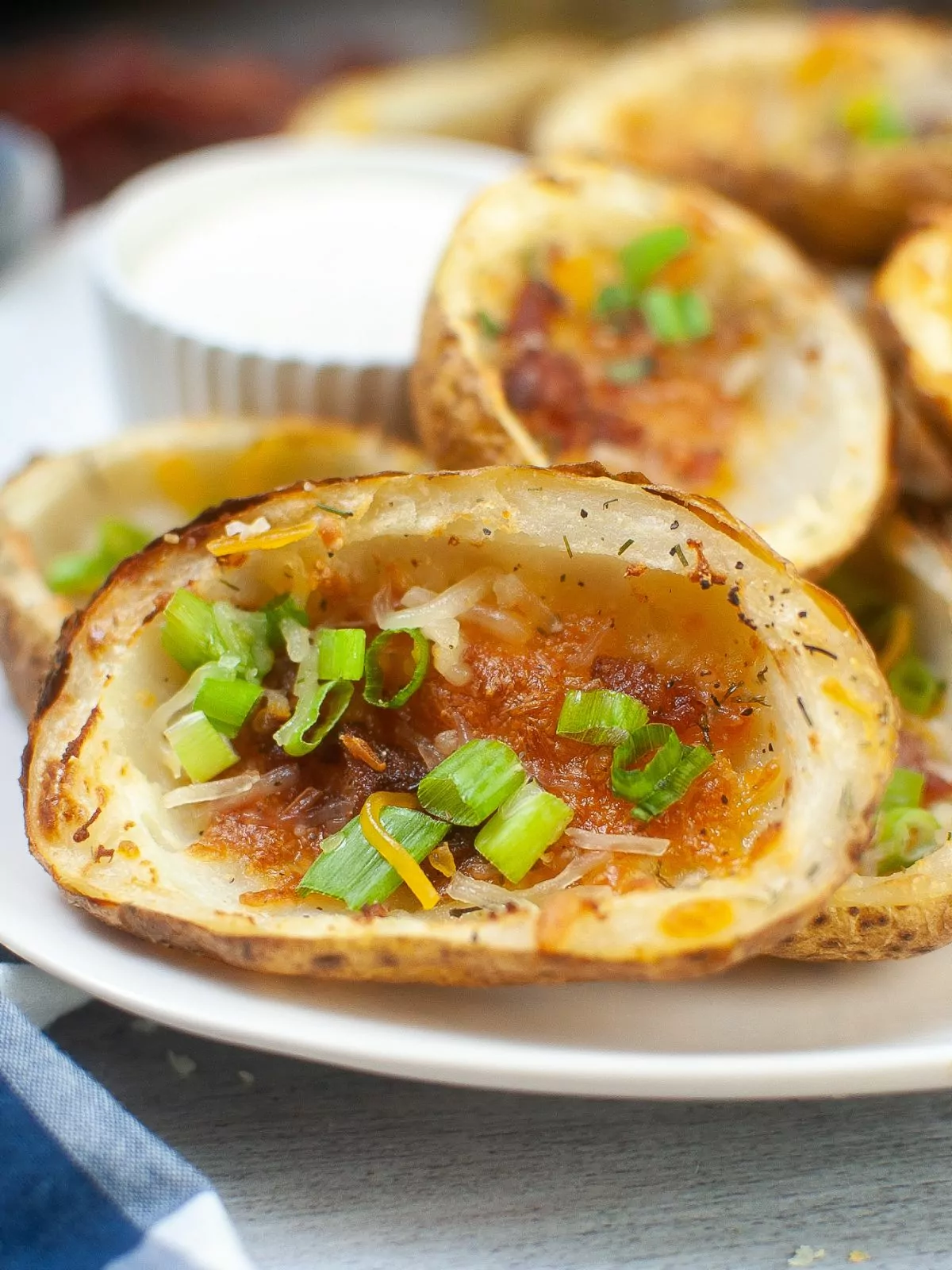 close up of a potato skin filled with melted cheese, bacon, and green onions