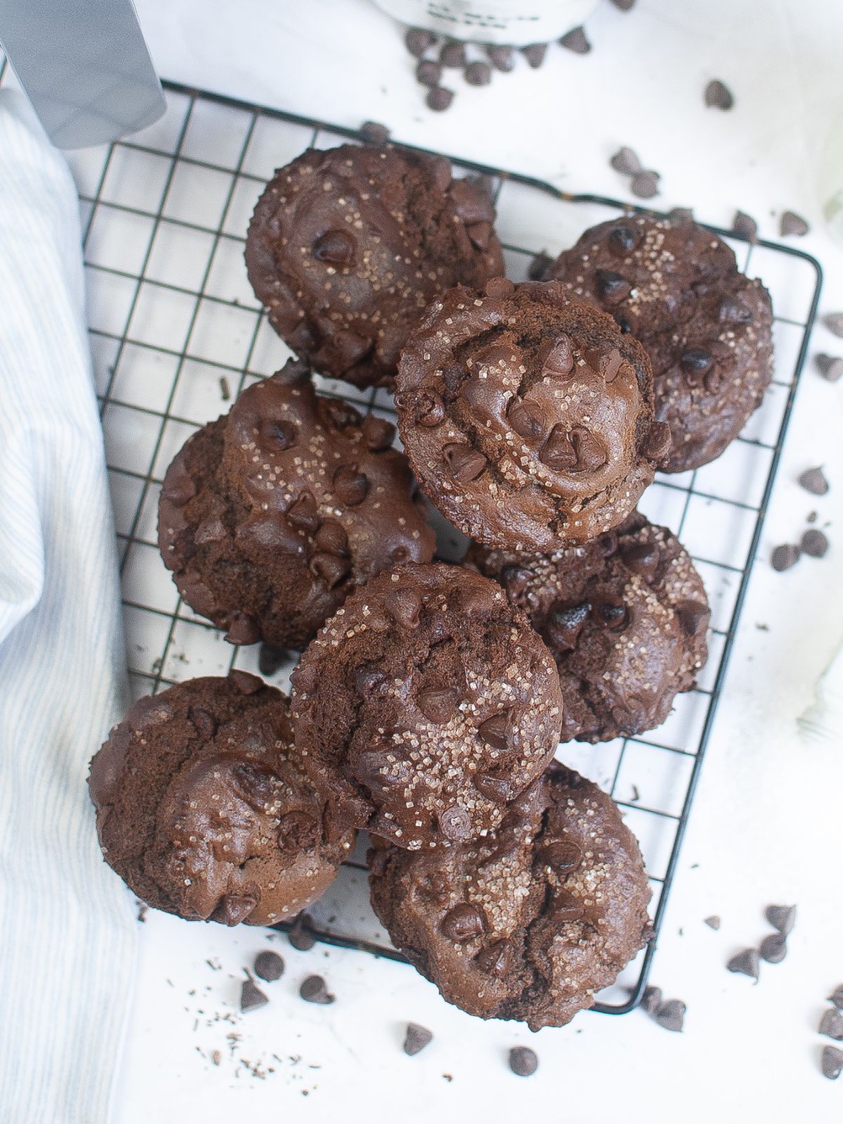 overhead view of a stack of air fryer chocolate muffins with chocolate chips on a wire rack