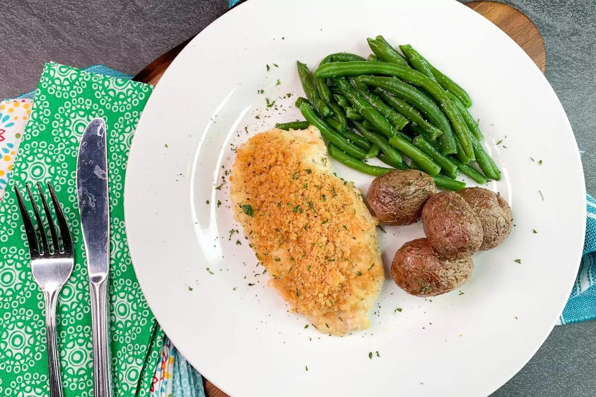 chicken with potatoes and green beans on white plate.