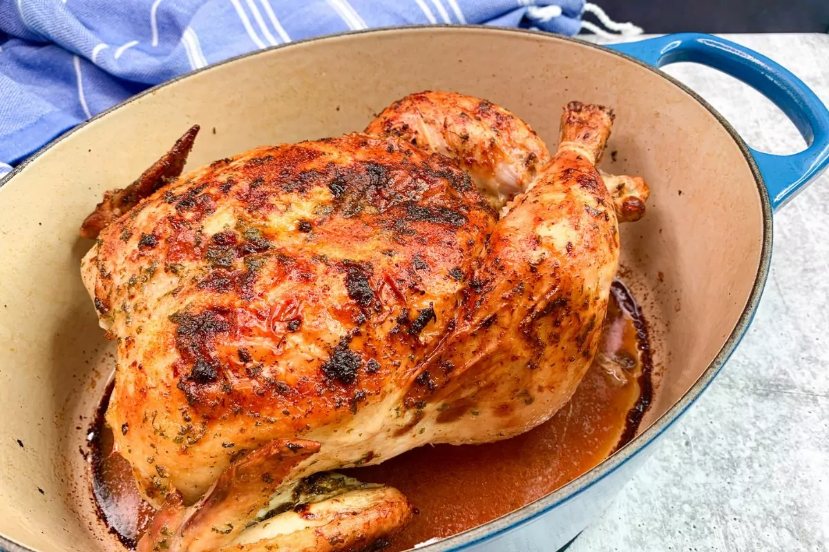 Roast chicken in blue Dutch Oven.