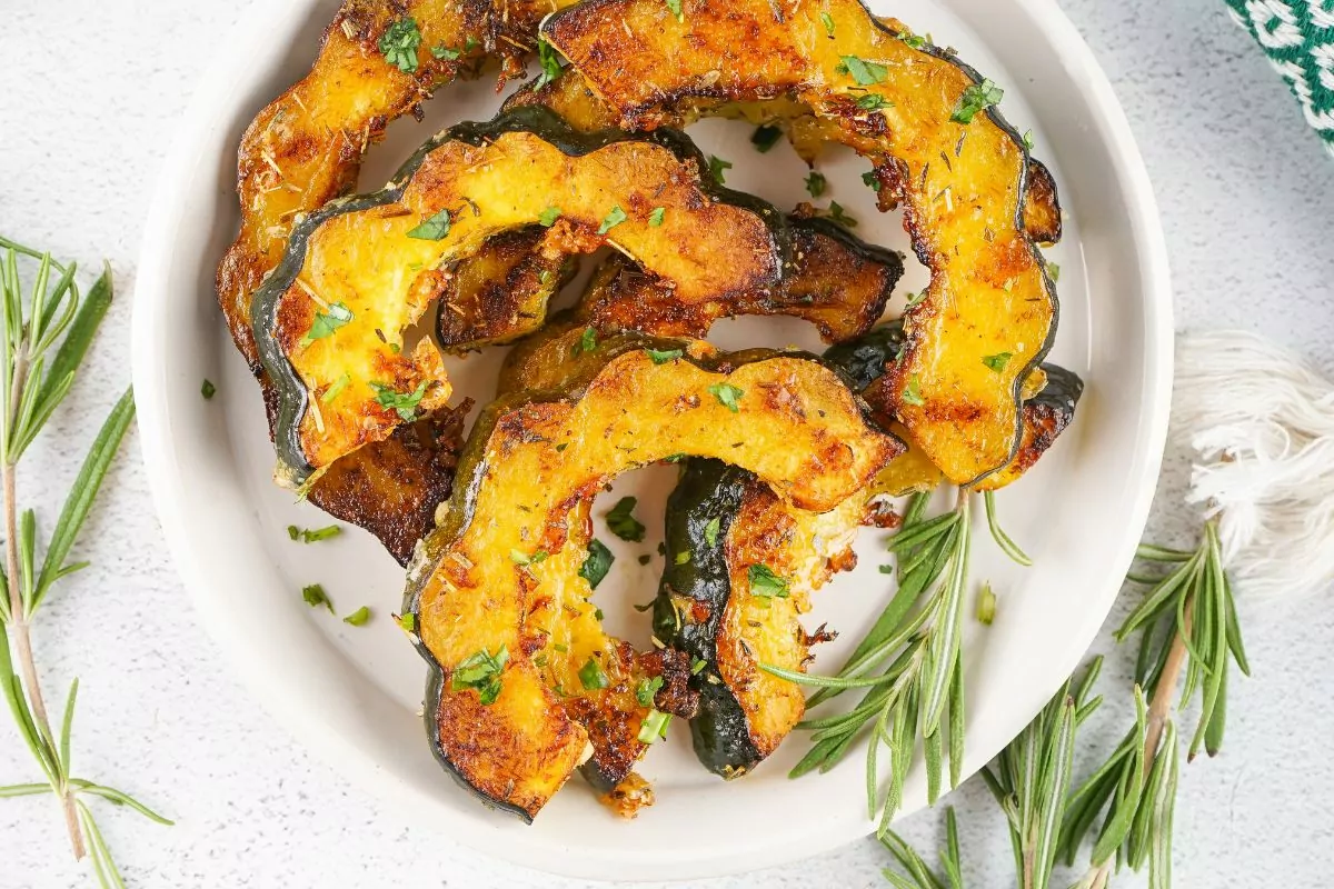 Roasted Acorn Squash Thanksgiving served on a white plate and fresh sprigs of rosemary around it.