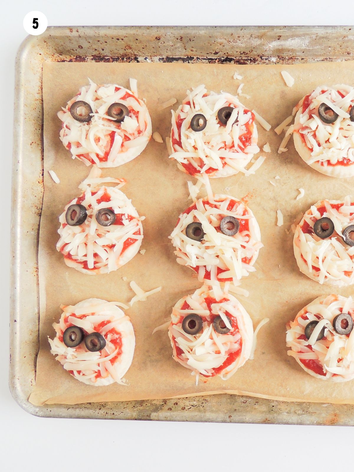 pizza circles with tomato sauce, cheese and black olives ready for the oven.