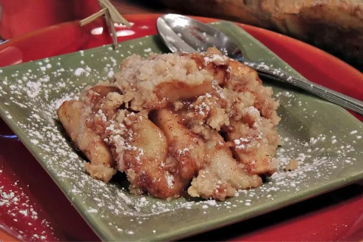 apple crisp on green plate with spoon.