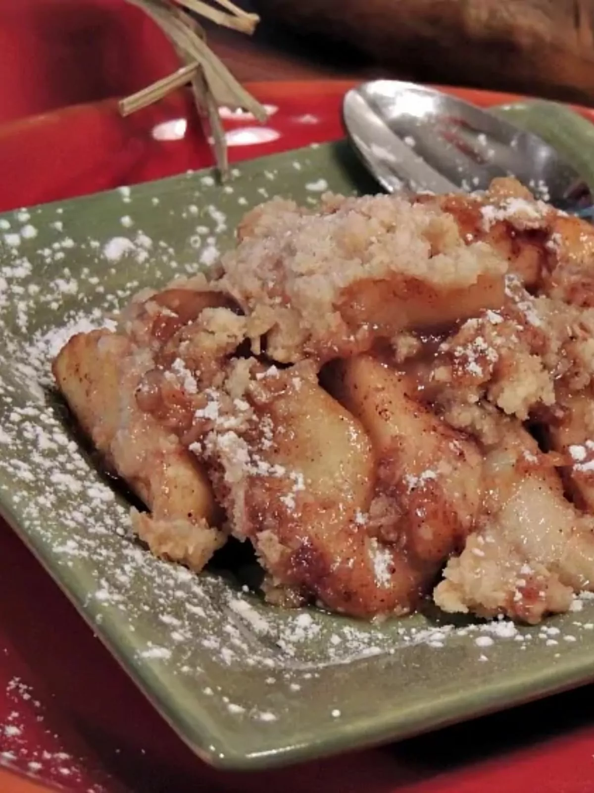 apple crisp on green plate with powdered sugar.