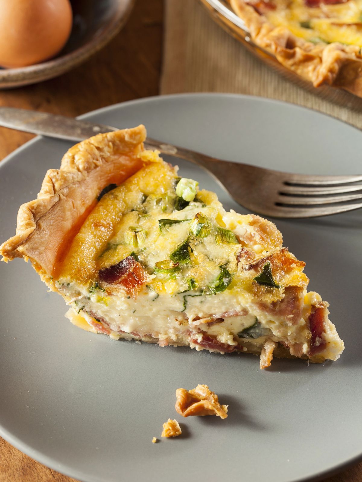 slice of quiche on gray plate with fork.