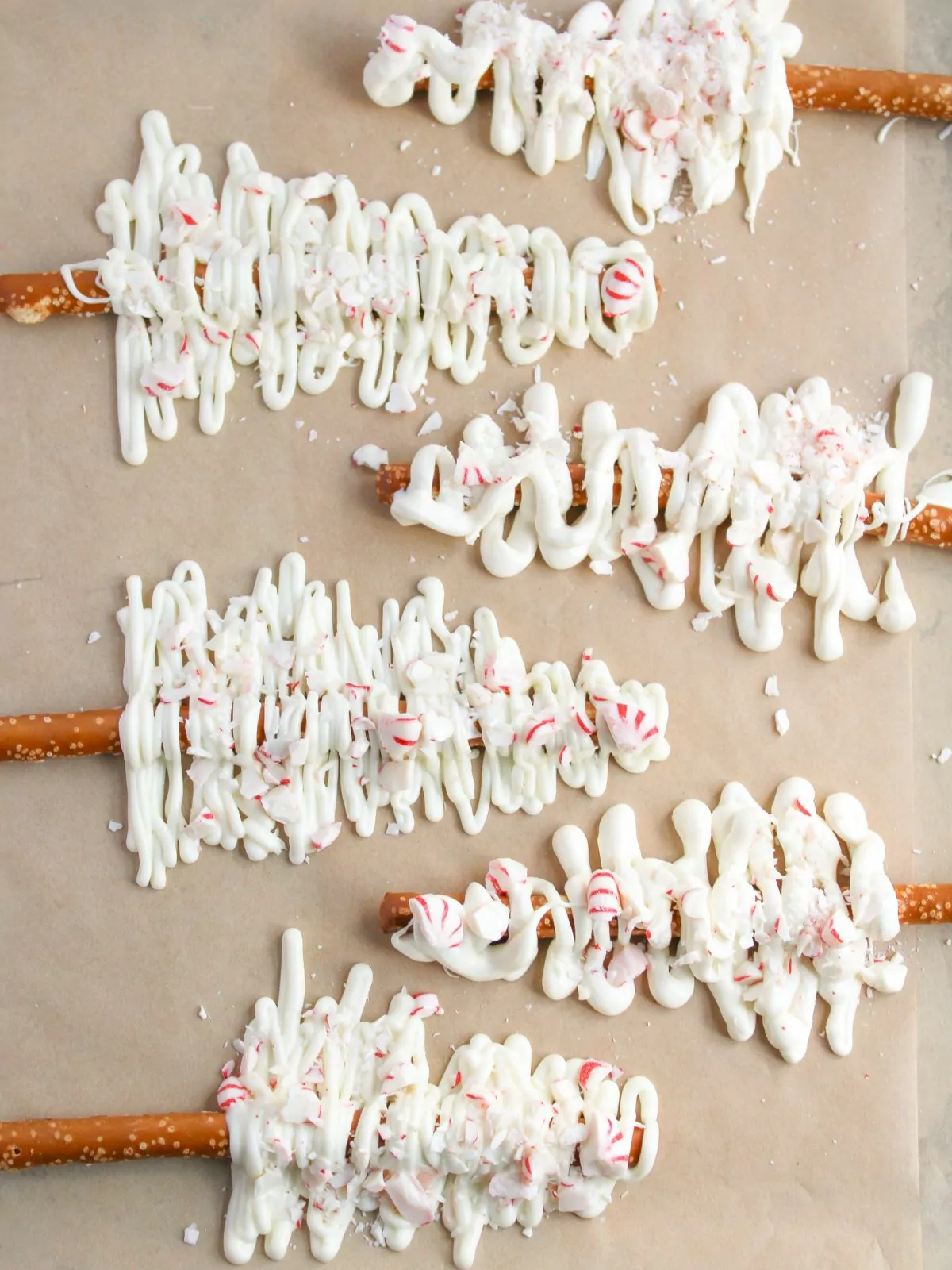 completed pretzel rod Christmas trees with white chocolate and crushed peppermints drying on a sheet of parchment paper