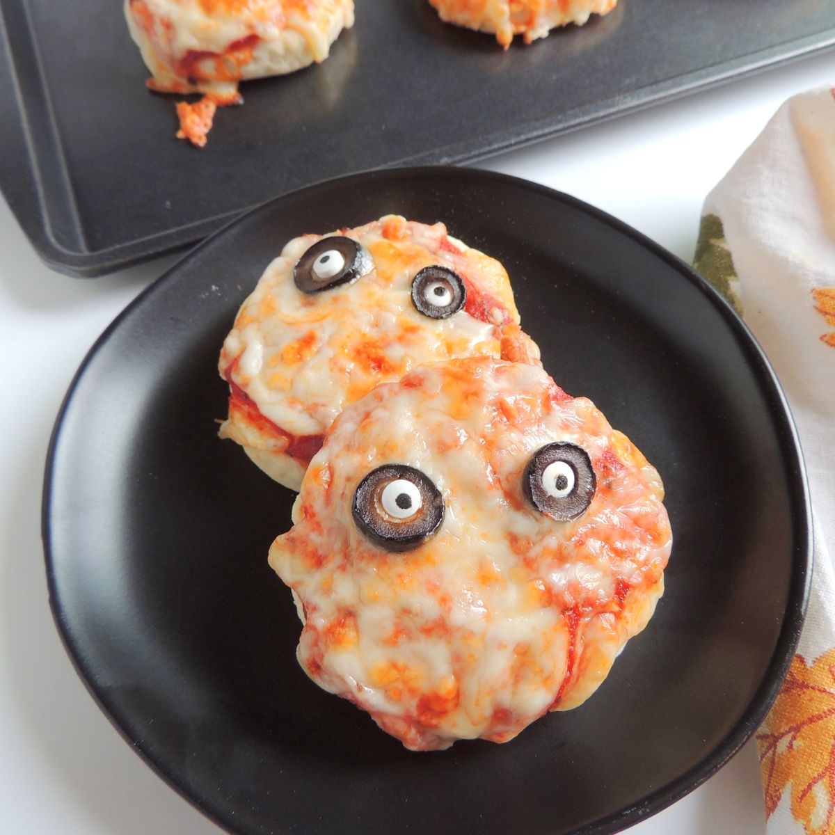 closeup of mini pizzas on black plate for Halloween.