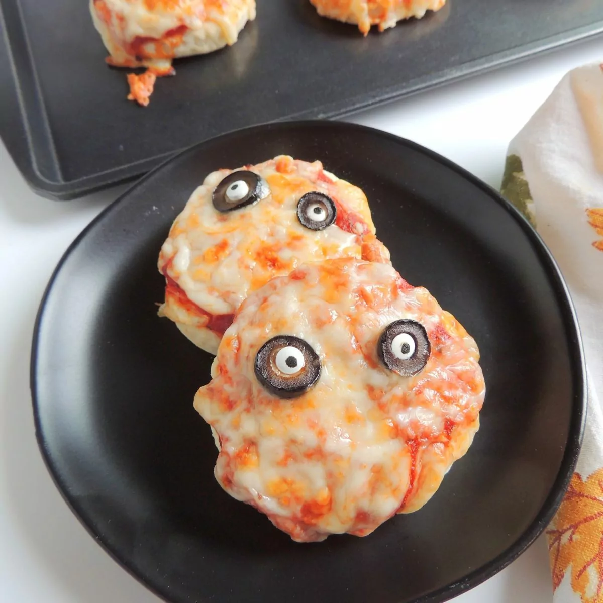 closeup of mini pizzas on black plate for Halloween.