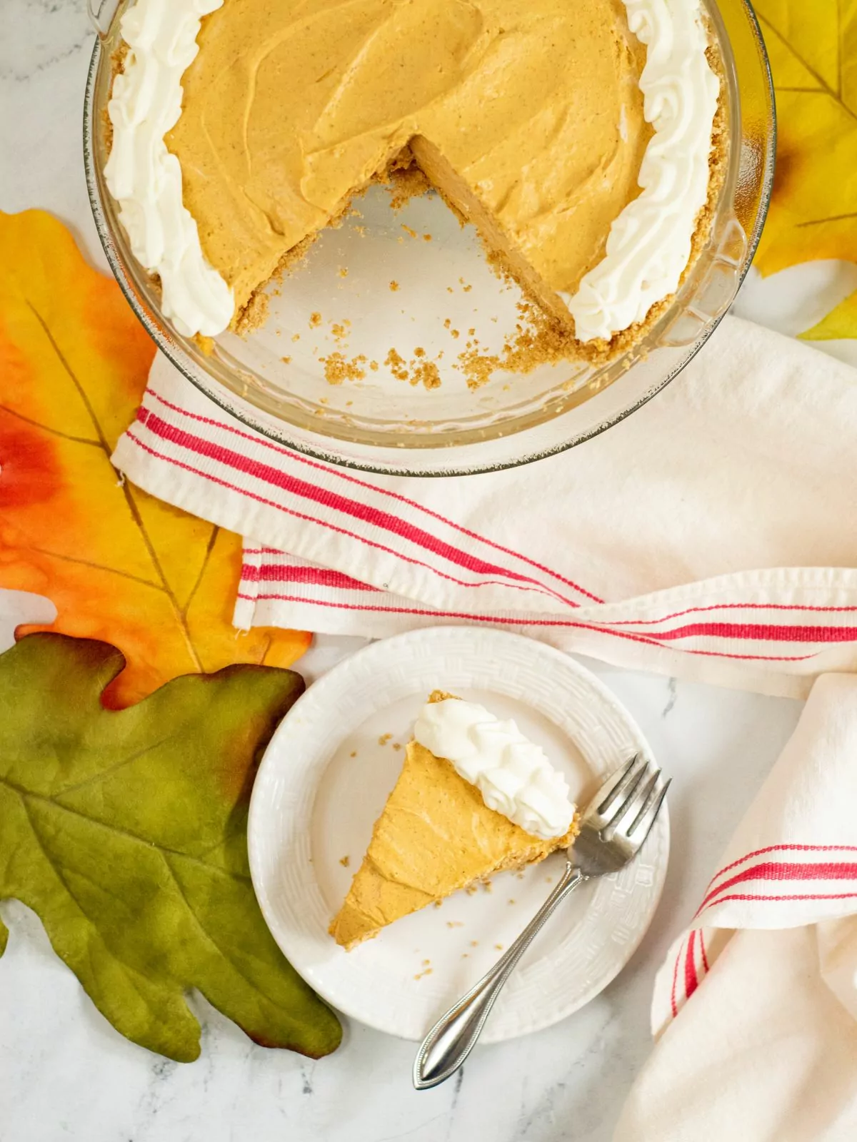 pumpkin cheesecake with graham cracker crust served on plate with whipped cream.