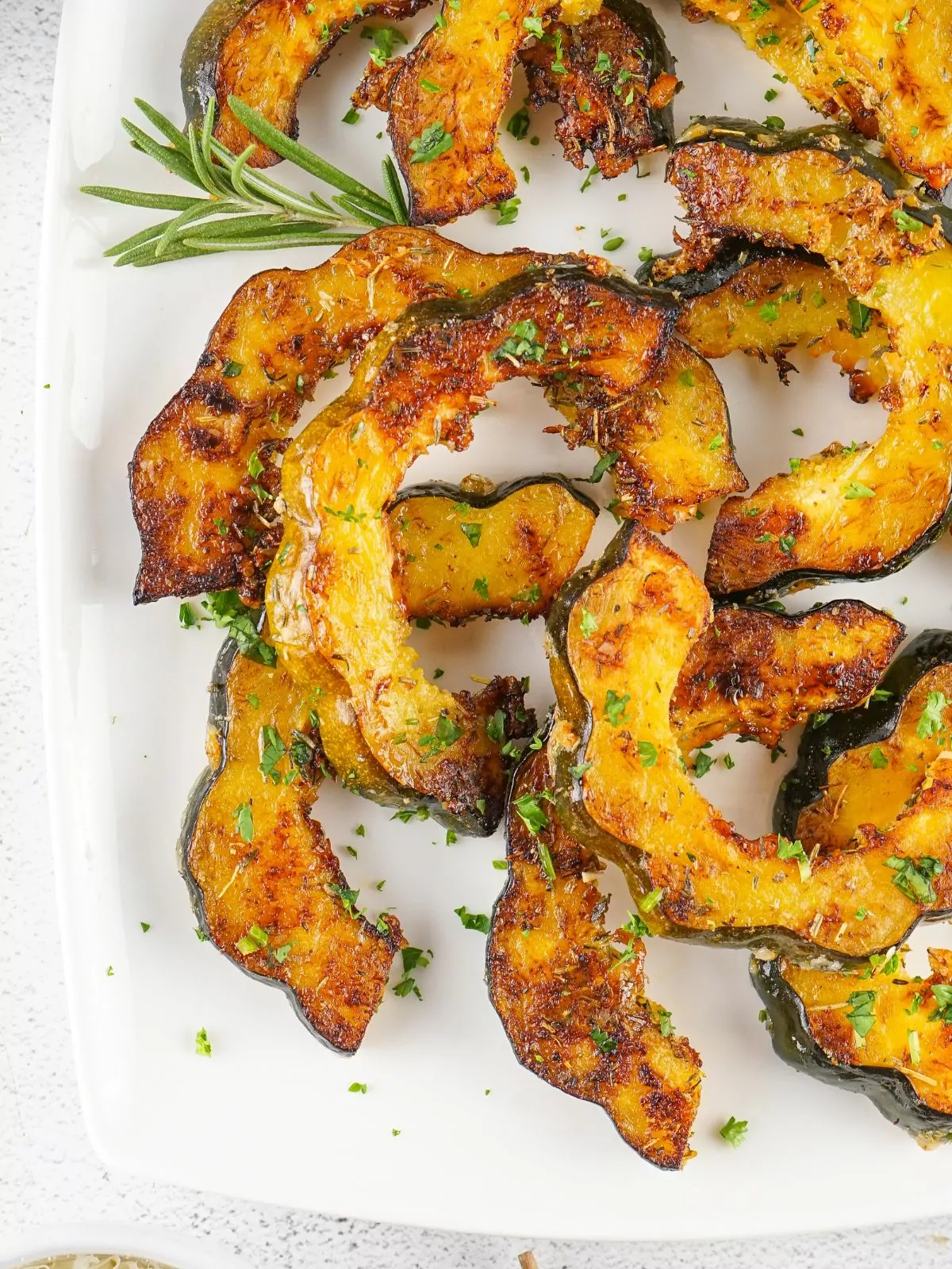 platter of roasted acorn squash with fresh sprig of rosemary