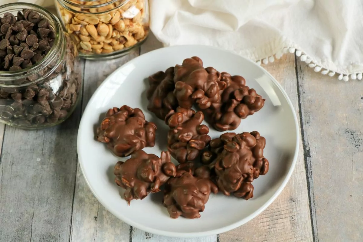 a plate of chocolate covered peanuts with two jars of peanuts and chocolate chips.