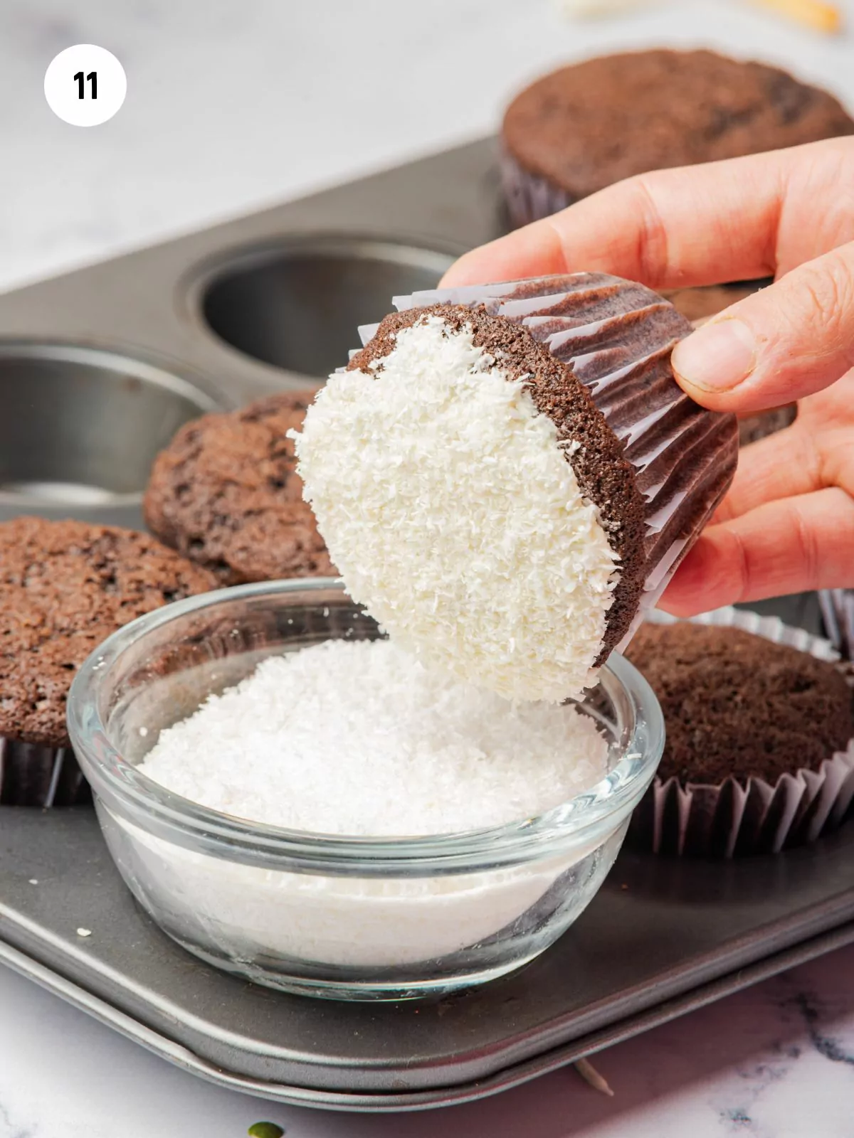 frosted cupcake being dipped into shredded cupcake